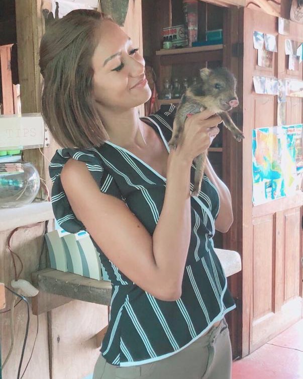 Gaudy smiling at the baby pecarí she's holding, at the rustic soda on the outskirts of town where they met